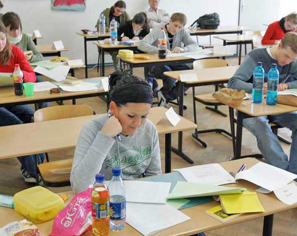 Das Foto zeigt mehrere Schüler an Tischen bei der Abiturprüfung.