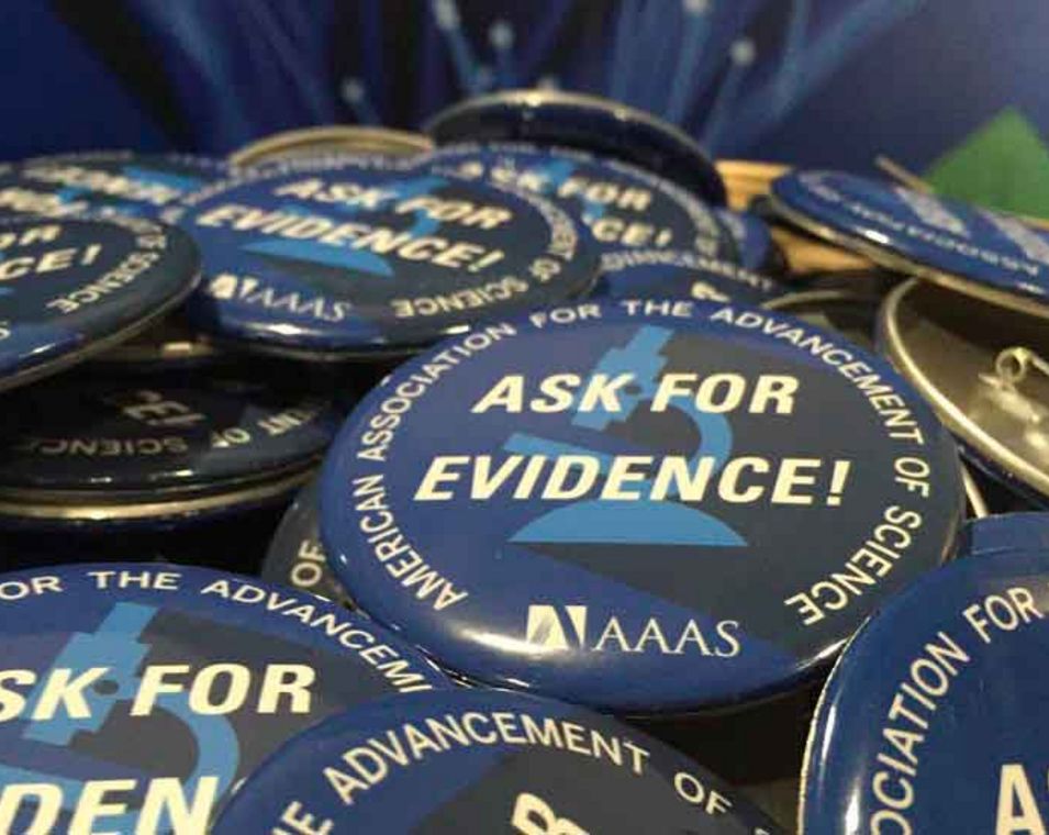 Ein Stapel Buttons bedruckt mit den Worten "Ask for Evidence" der US-amerikanischen Forschervereinigung AAAS