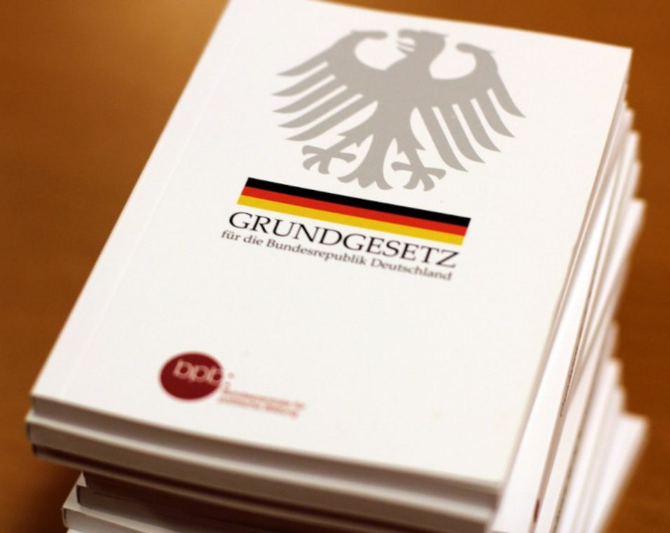 Das Bild zeigt einen Bücherstapel mit der Aufschrift "Grundgesetz für die Bundesrepublik Deutschland".