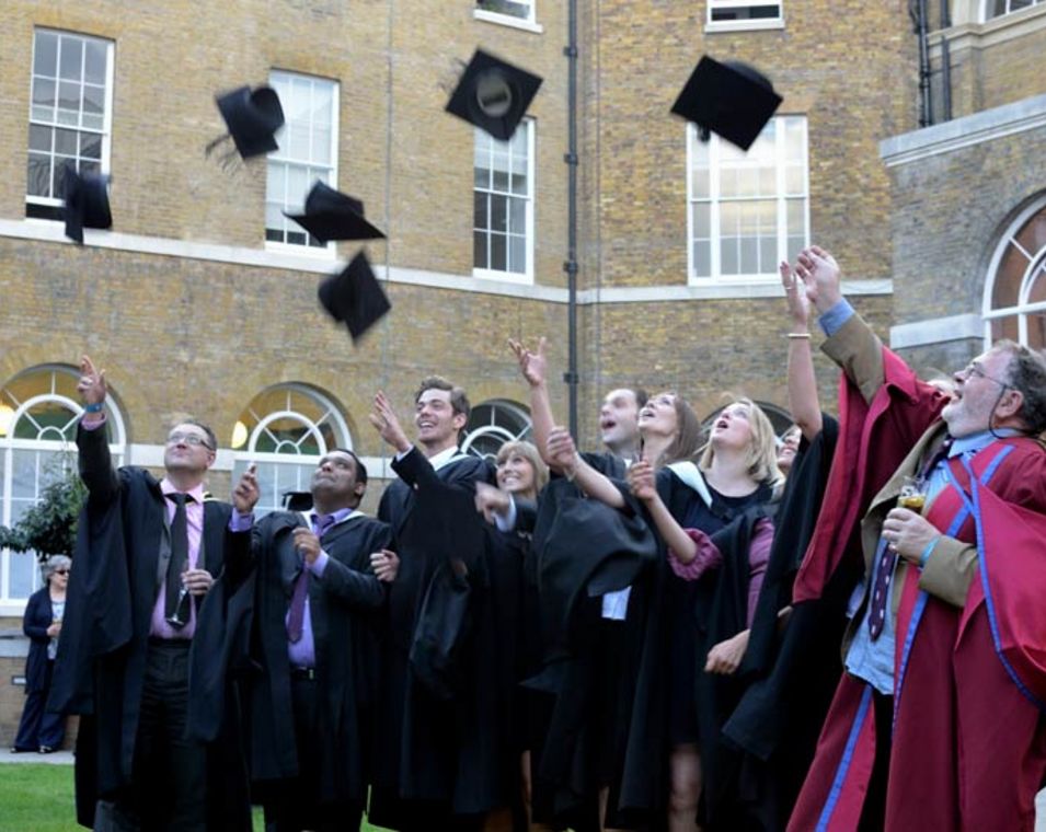 Studierende an einem britischen College haben ihren Abschluss bestanden und werfen ihre Hüte in die Luft. 