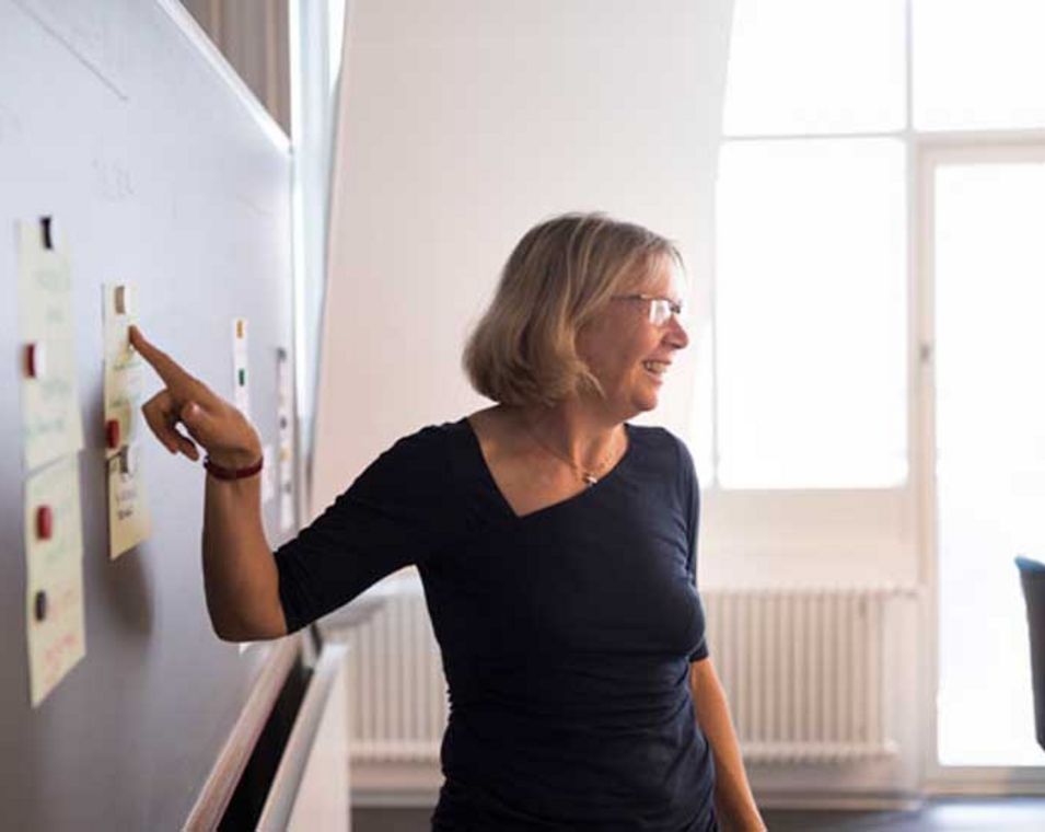 Das Foto zeigt eine Professorin vor einer Tafel in einem Hörsaal.