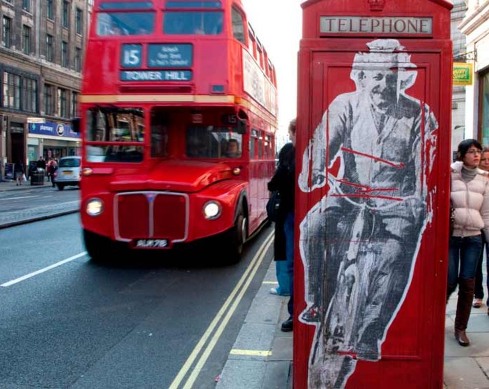 Roter Doppeldeckerbus und rote Telefonzelle mit einem Bild von Albert Einstein auf dem Fahrrad