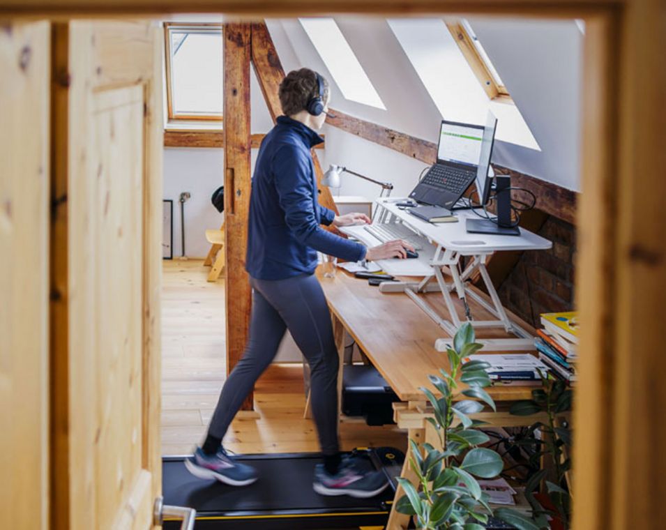 Ein Mann arbeitet am Computer und läuft gleichzeitig auf einem Laufband. 