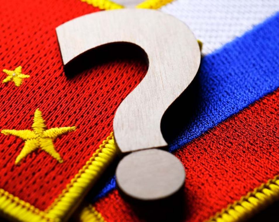 Die russische und die chinesische Flagge sind gekreuzt übereinander gelegt zu sehen mit einem großen Fragezeichen darüber. 