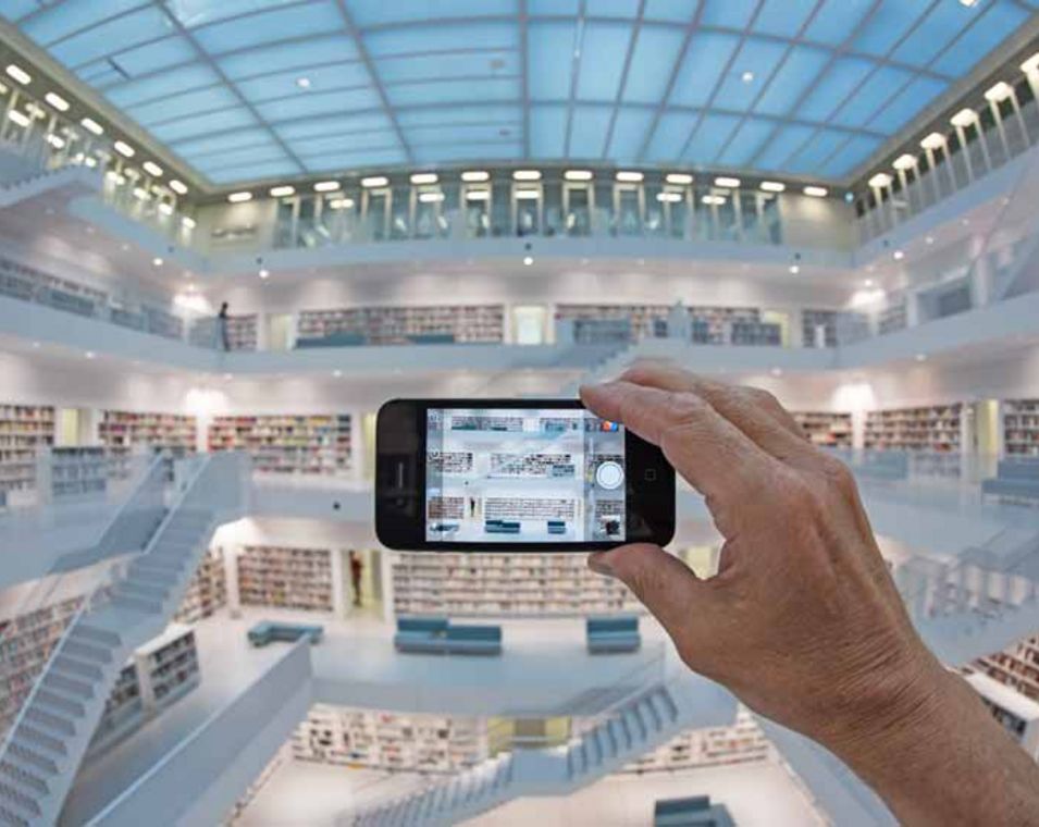 Mann mit Smartphone fotografiert Galeriesaal mit Treppenaufgängen der Stadtbibliothek Stuttgart