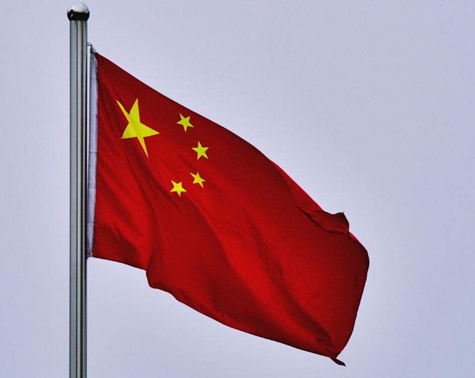 Die chinesische Flagge vor grauem Himmel.