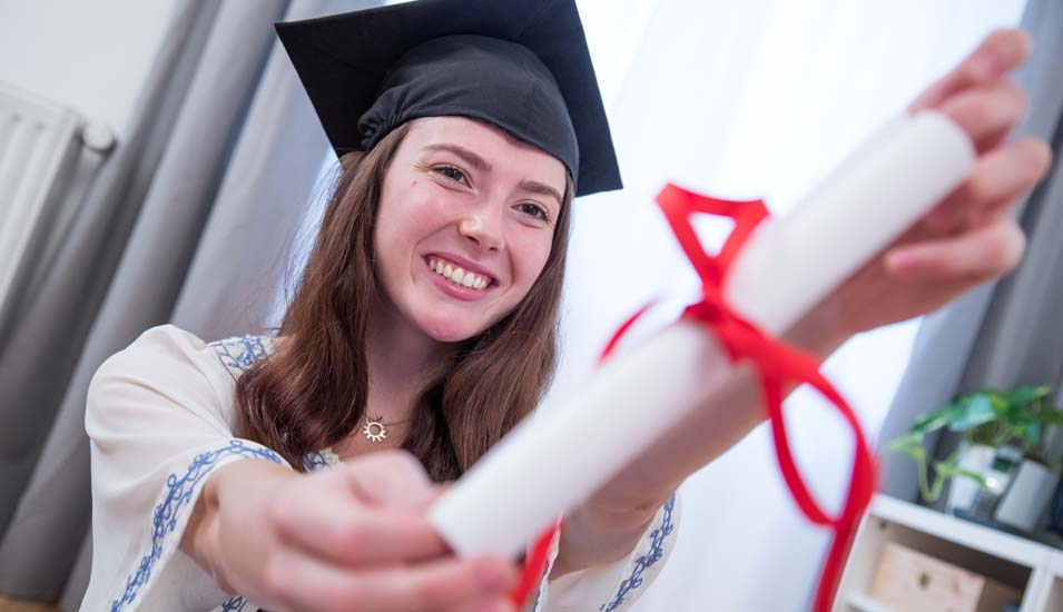 Junge Frau mit Doktorhut und Diplom mit roter Schleife
