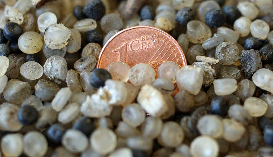 Das Foto zeigt Kügelchen mit Mikroplastik und einem Centstück.