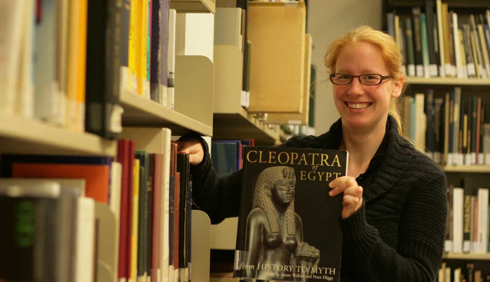 Das Foto zeigt eine Mitarbeiterin des Instituts für Ägyptologie der Uni Münster an einem Bücherregal.