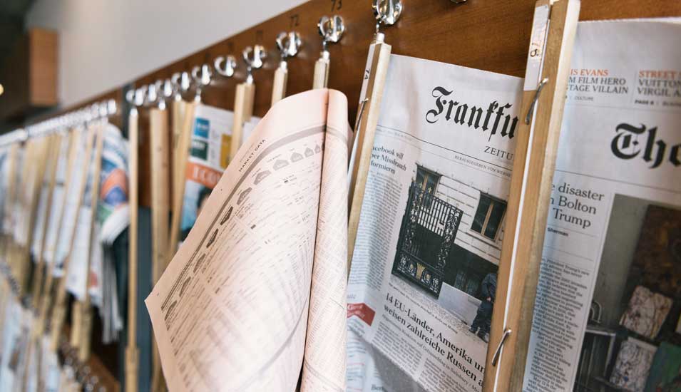 Das Foto zeigt Zeitungen an einem Ständer in einem Café