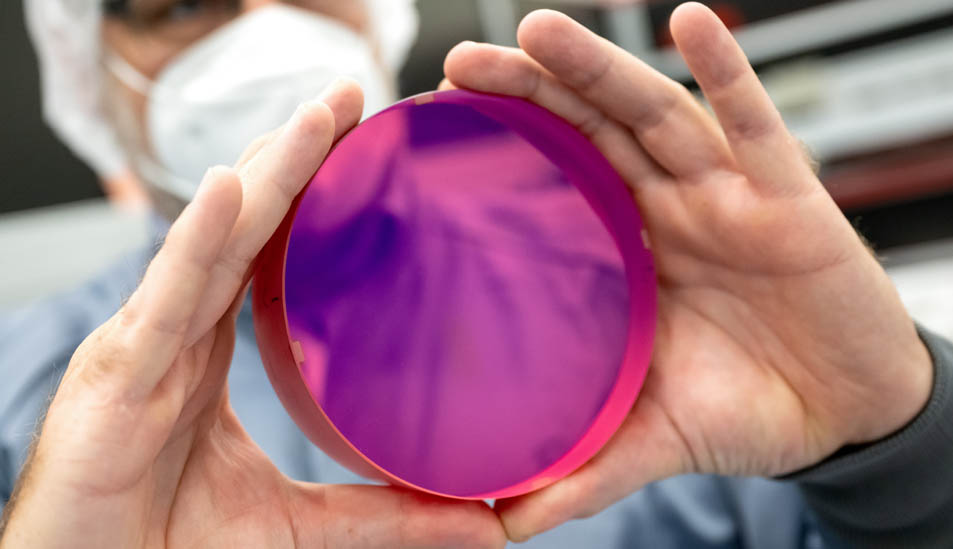 Wissenschaftler hält einen violetten Laserkristall in die Höhe