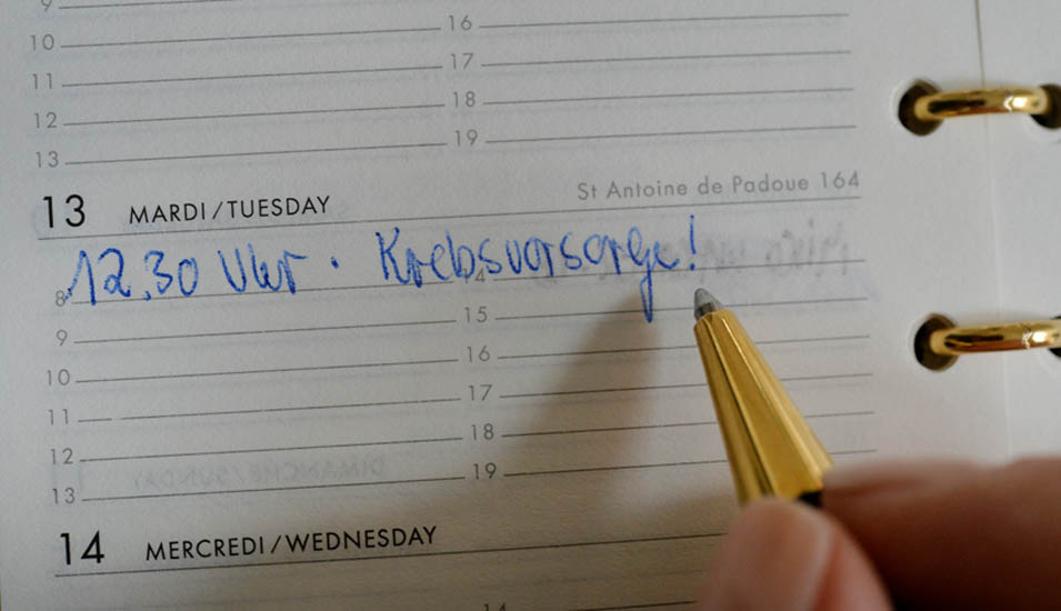 Eine Person trägt mit einem Kugelschreiber einen Krebsvorsorge-Termin in ihren Kalender ein.
