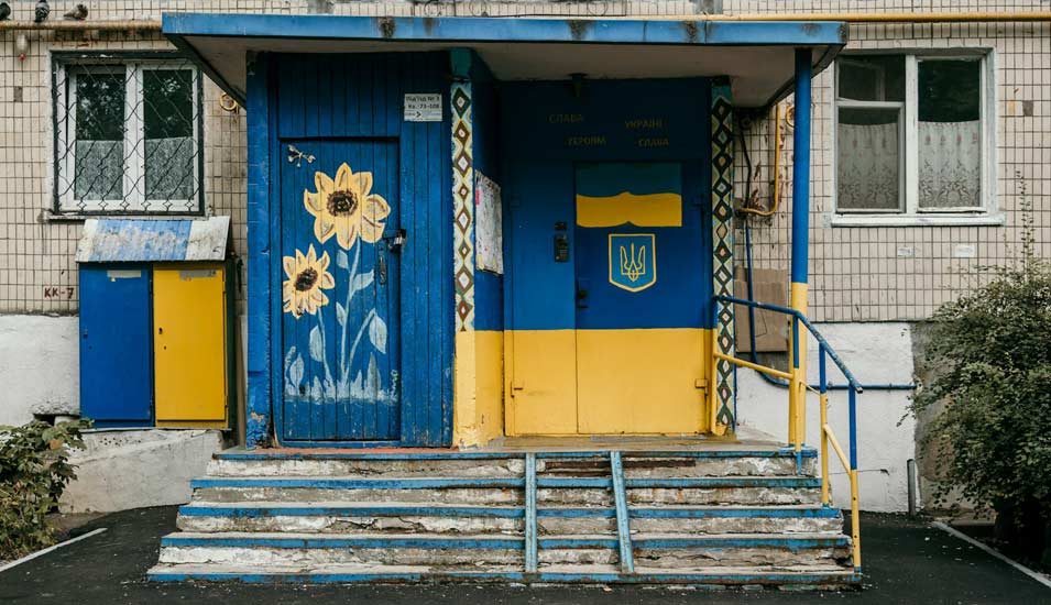 Eine Häuerfront samt Tür ist in den ukrainischen Nationalfarben bemalt. Eine Sonnenblume ziert zudem eine Tür. 