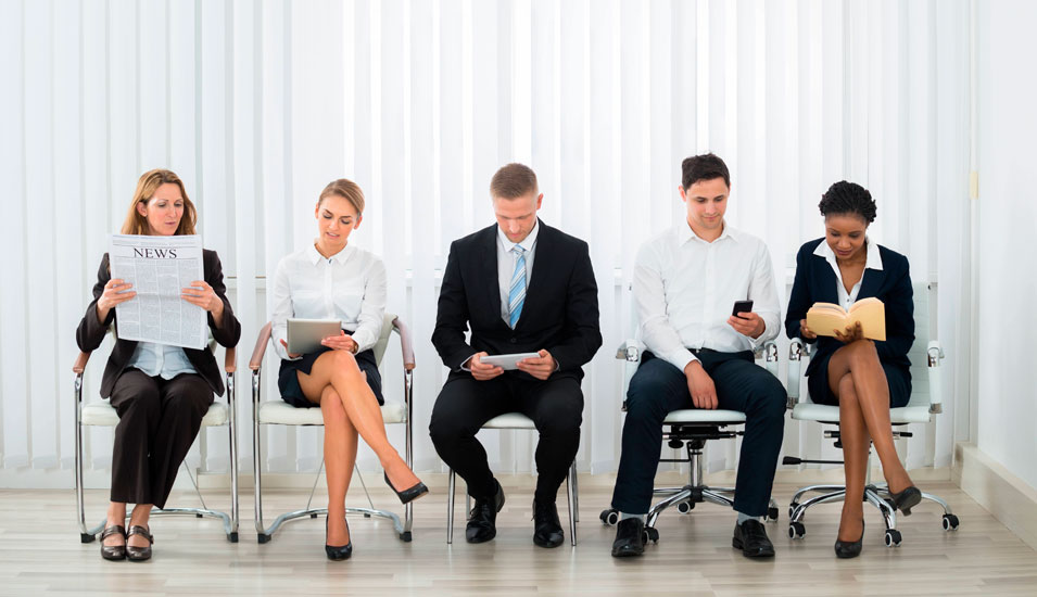 Das Foto zeigt Männer und Frauen, die auf ein Bewerbungsgespräch warten