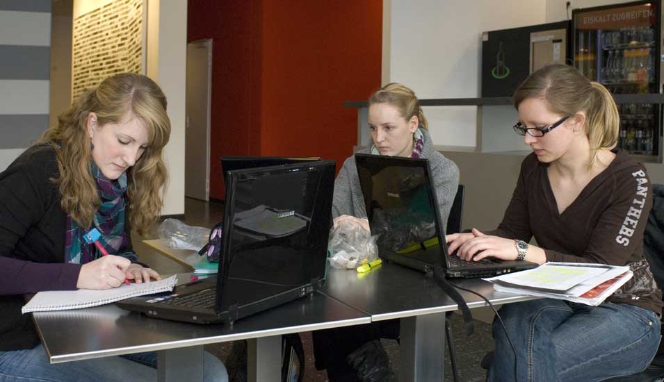 Das Foto zeigt drei Studentinnen mit Notebooks an der Universität Dortmund.