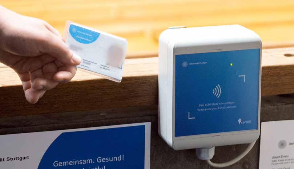 Ein Student hält in einem Hörsaal der Universität Stuttgart seine Zugangskarte mit dem digitalen 2G-Nachweis an einen Scanner. 