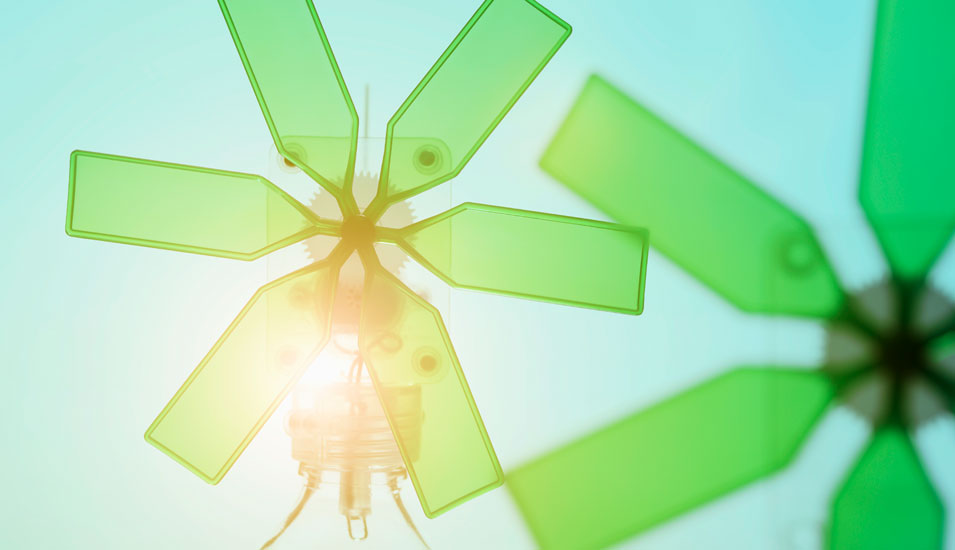 Grüne WIndmühlen, die mit einer Glühbirne verbunden sind (Symbolbild für Nachhaltigkeit)