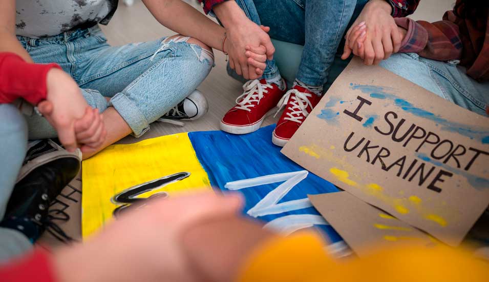 Studierende sitzen im Kreis um eine Ukraineflagge, daneben ein Schild "I support Ukraine"