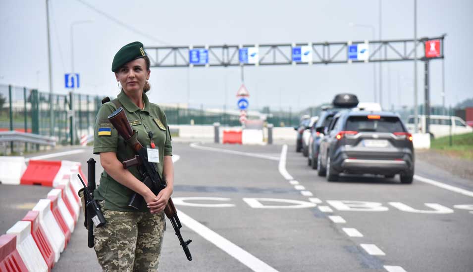 Checkpoint "'Krakovets - Korchova" an der ukrainisch-polnischen Grenze: Eine bewaffnete ukrainische Grenzbeamtin und passierende Autos.