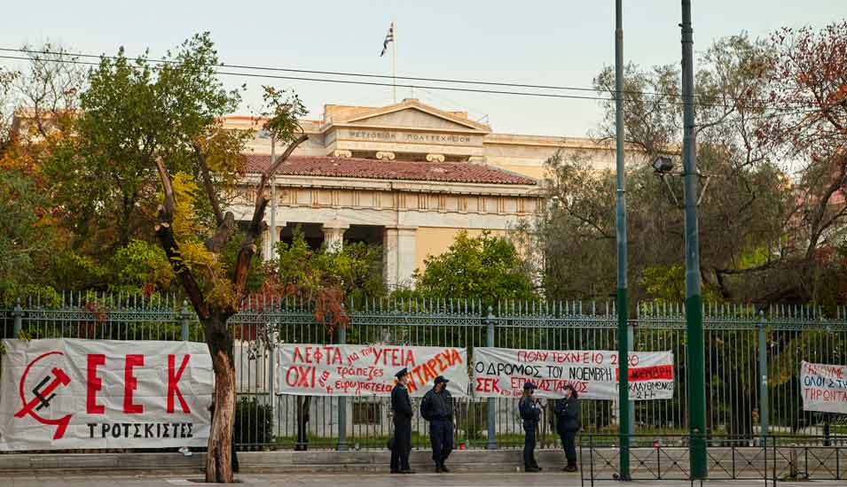 Protestplakate und Sicherheitskräfte vor der Technischen Universität Athen