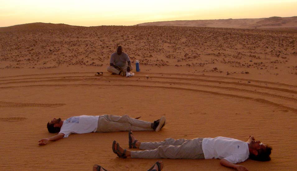 Forscherteam liegt am Abend auf dem Boden in der Wüste