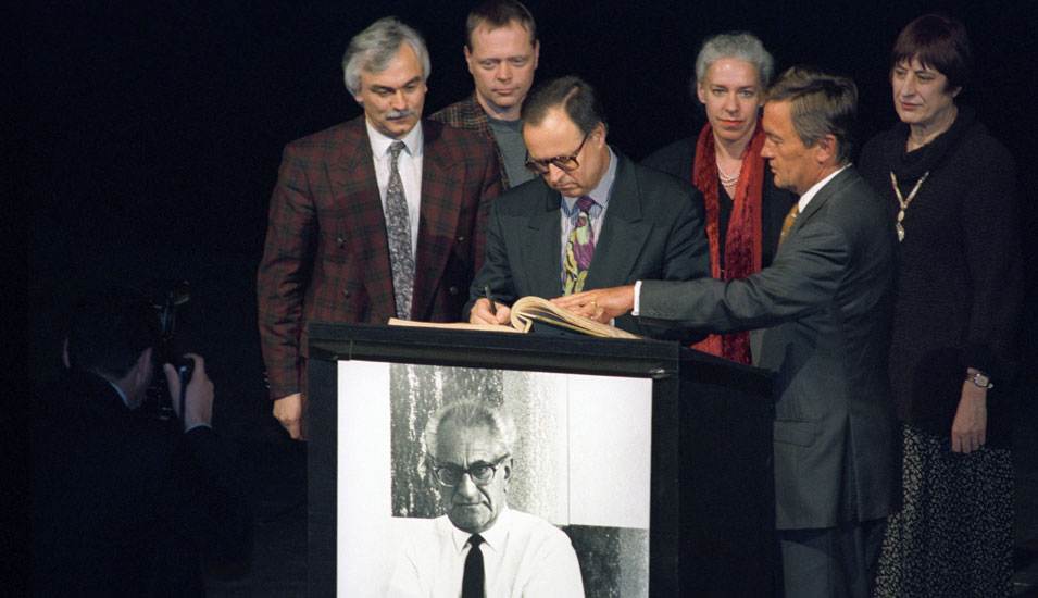 Hessens Ministerpräsident Hans Eichel unterzeichnet 1995 das Goldene Stiftungsbuch der Stadt Frankfurt am Main, das auf einem Pult mit dem Portrait von Fritz Bauer liegt