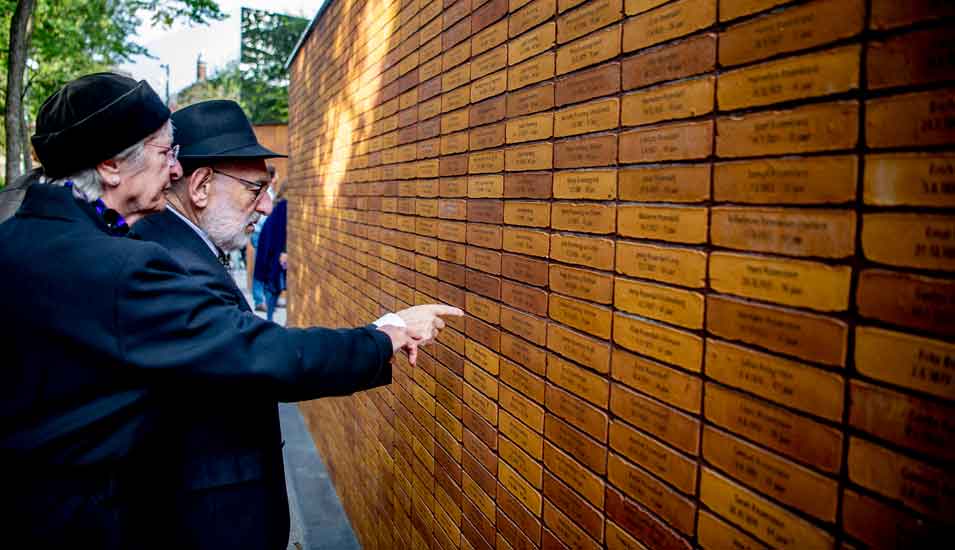 Besucher zeigen auf Namen ermordeter Juden auf dem Holocaust Namenmonument in Amsterdam.
