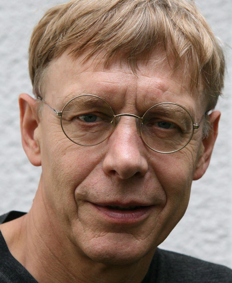 Ein Mann mit dunkelblondem, kurzem Haar und Brille ist im Porträt zu sehen 