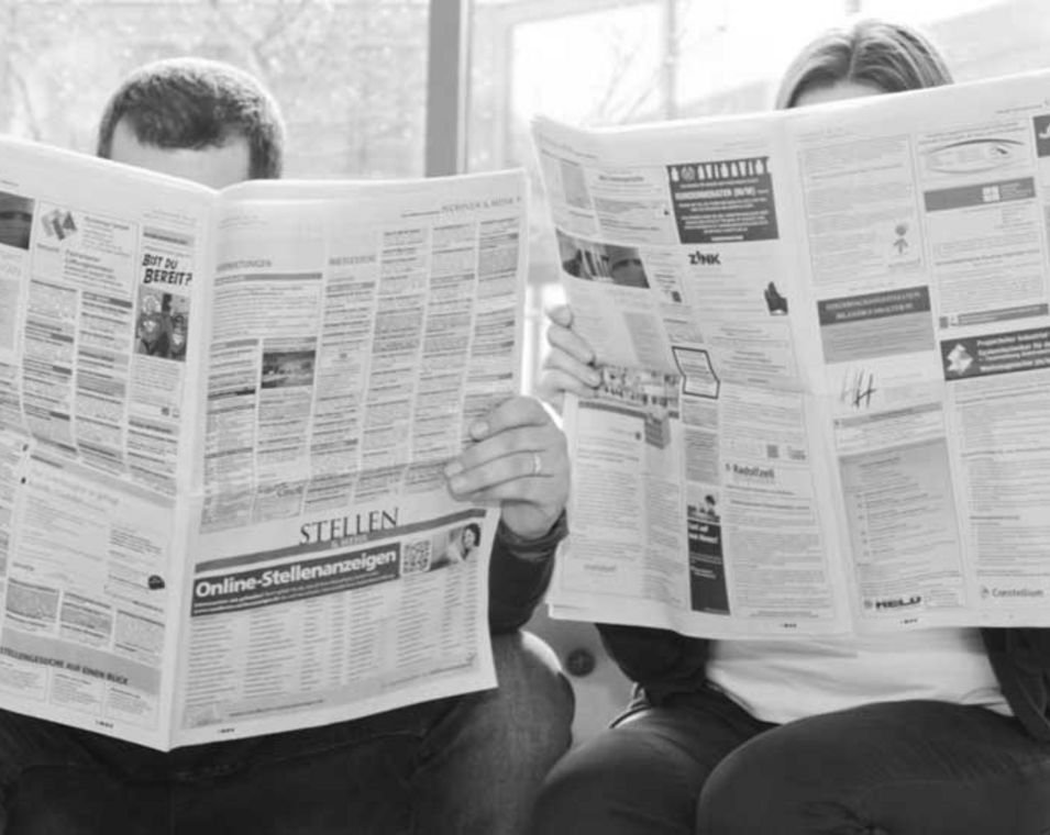 Frau und Mann suchen nach Stellen in einer Zeitung