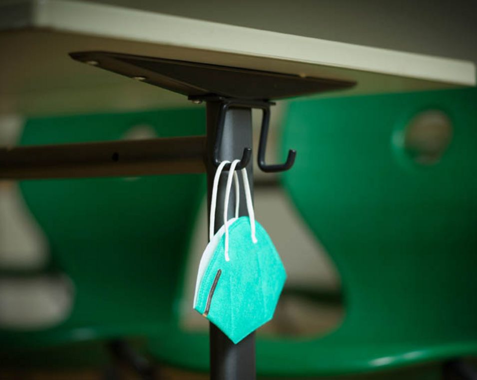 Eine Atemschutzmaske hängt an einem Tisch in einer Schule