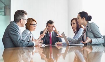 Fünf Beschäftigte sitzen diskutierend an einem Tisch 