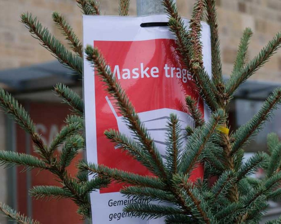 Tannenbaum mit Hinweisschild zum Tragen einer Maske