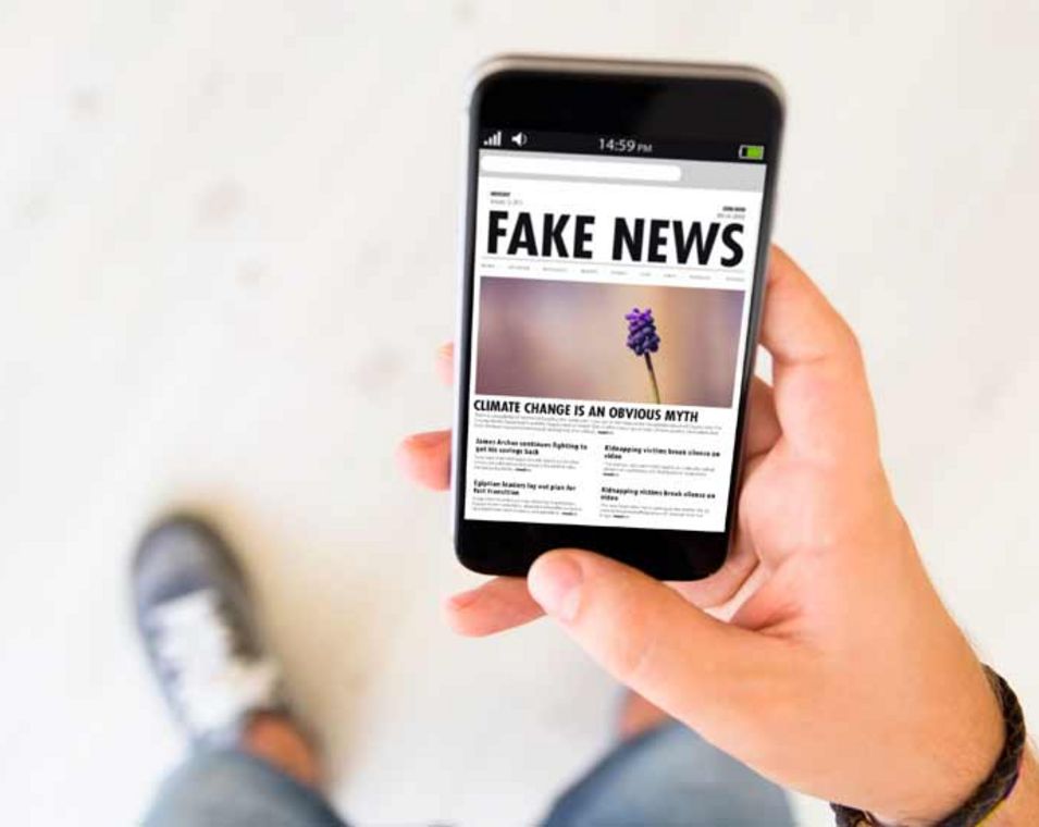 Hand einer Person, die auf dem Smartphone Fake News liest