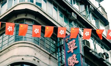 Leine mit kleinen Flaggen von China and Hongkong vor einer Häuserzeile in Hongkong aus der Kolonialzeit