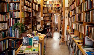 Blick in einen Buchladen: Viele Bücher in Regalen und Stapeln