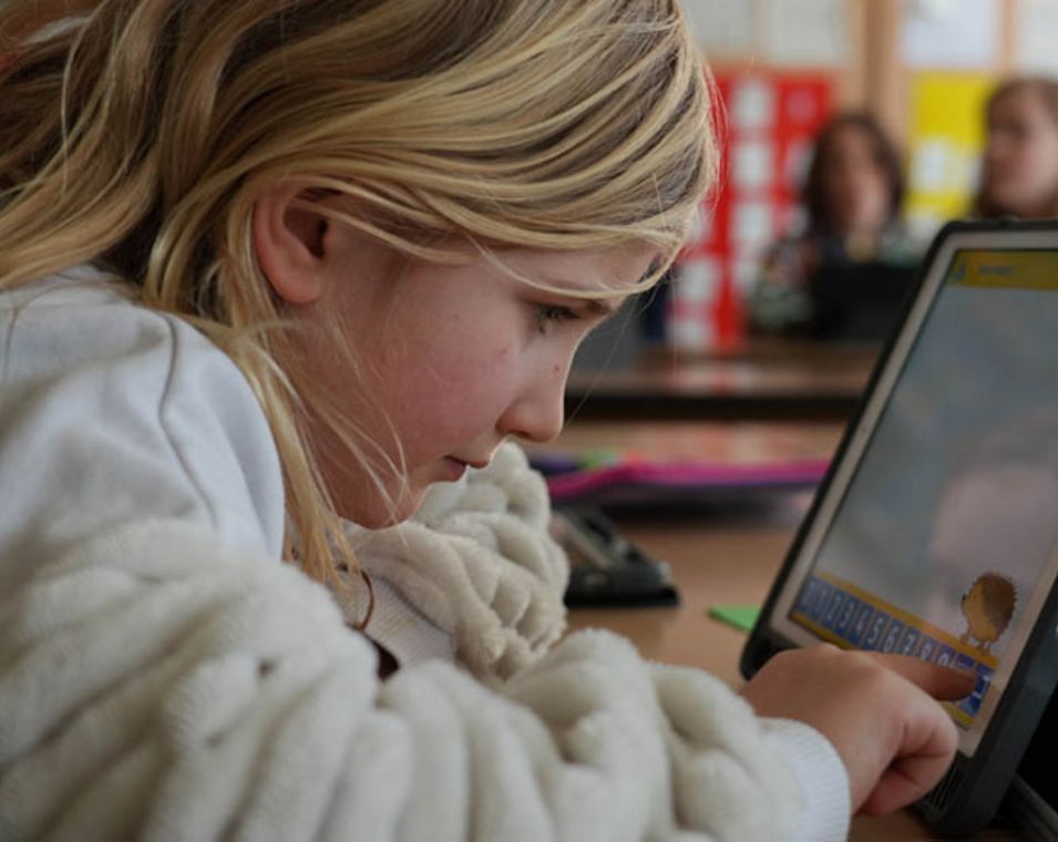 Ein Mädchen sitzt in der Schule an einem Tablet