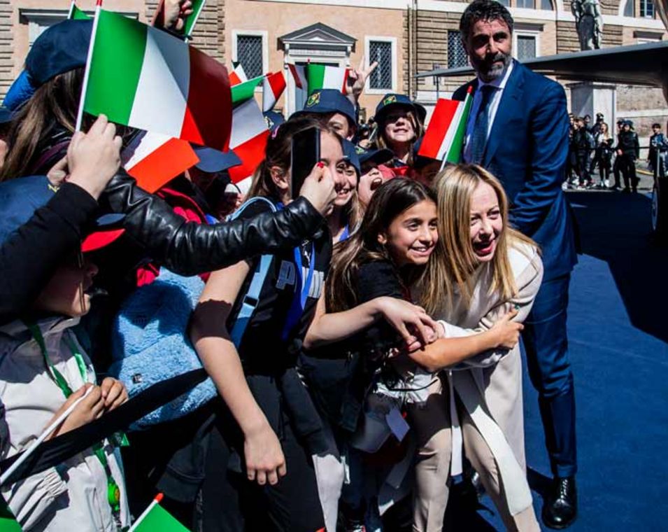 Die italienische Ministerpräsidentin Giorgia Meloni umringt von Kindern mit Italien-Fähnchen