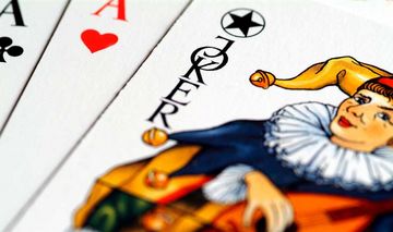 Drei Spielkarten: Ein Joker mit Narrenkappe und zwei Asse