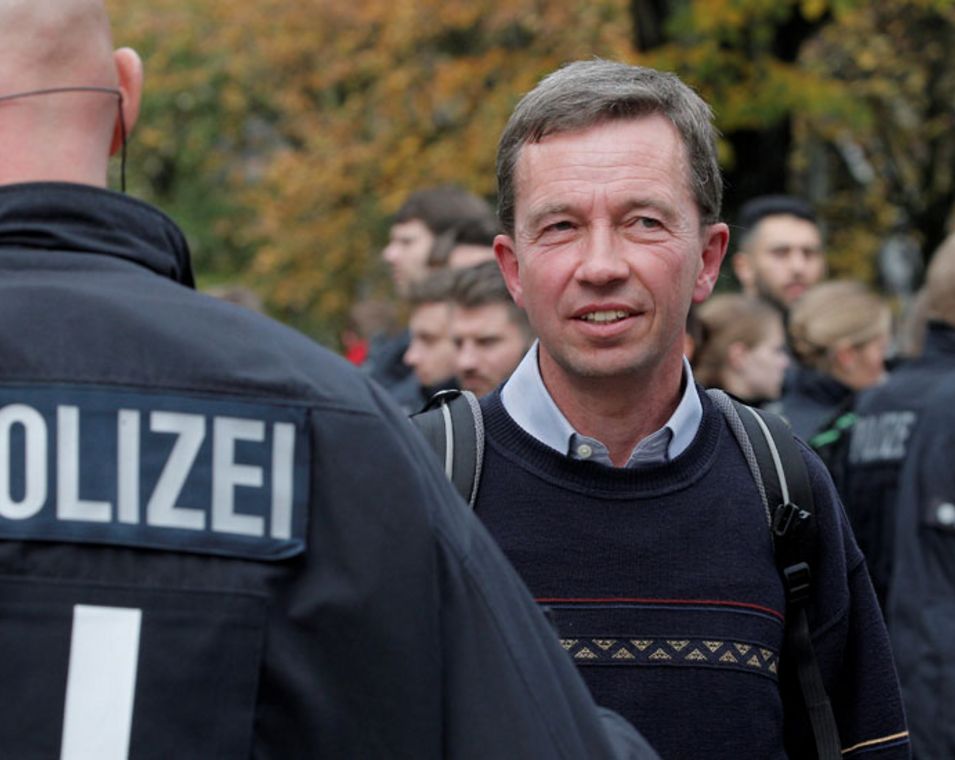 Das Foto zeigt Professor Bernd Lucke geschützt von Polizisten in Uniform