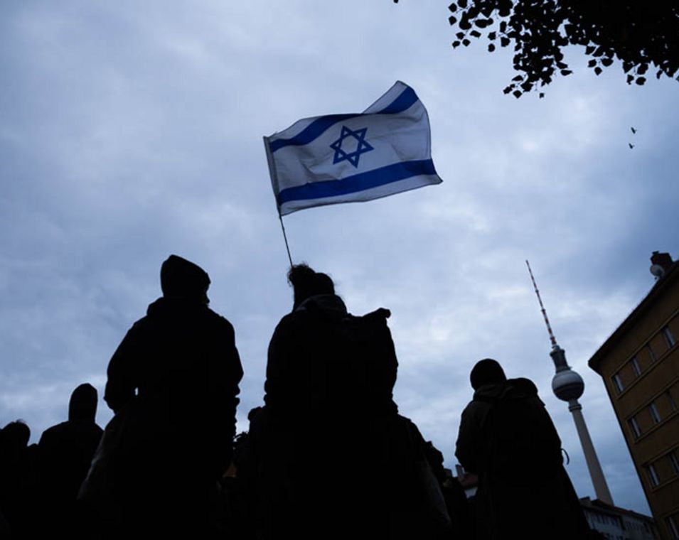 Zwei Menschen halten eine Israel-Flagge in Berlin in die Höhe.