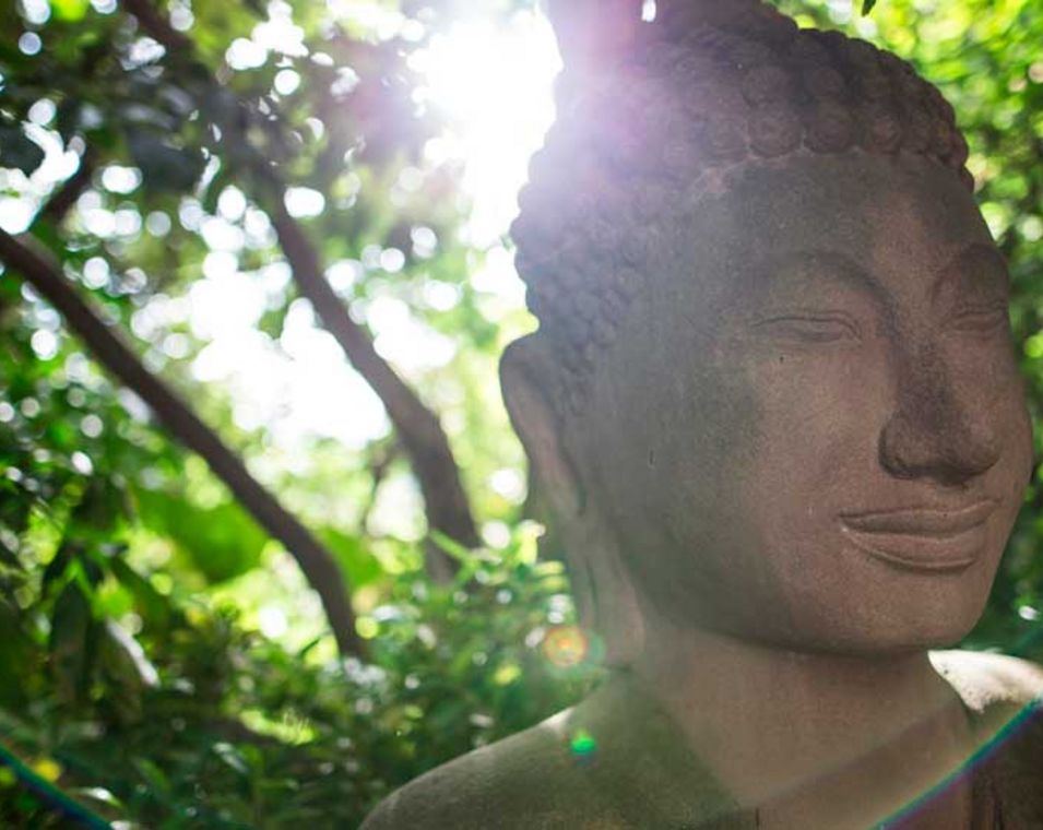 Buddha-Skulptur mit Sonnenlicht von hinten, das einen Heiligenschein erzeugt