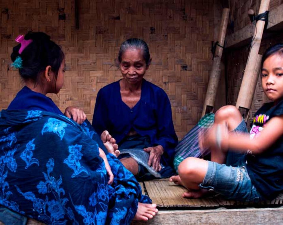 Eine Seniorin und zwei Mädchen sitzen auf einer Veranda in Indonesien