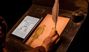Person zeichnet mit einer Feder zwei Papageien von einer digitalen Vorlage ab