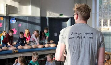 Philipp Humbsch steht beim Erste-Hilfe-Kurs vor einer Grundschulklasse
