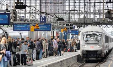 einfahrender Zug am Kölner Hauptbahnhof an einem Bahnsteig voller Reisender