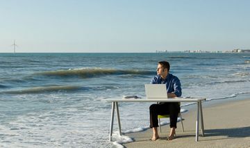 Mann am Schreibtisch am Strand