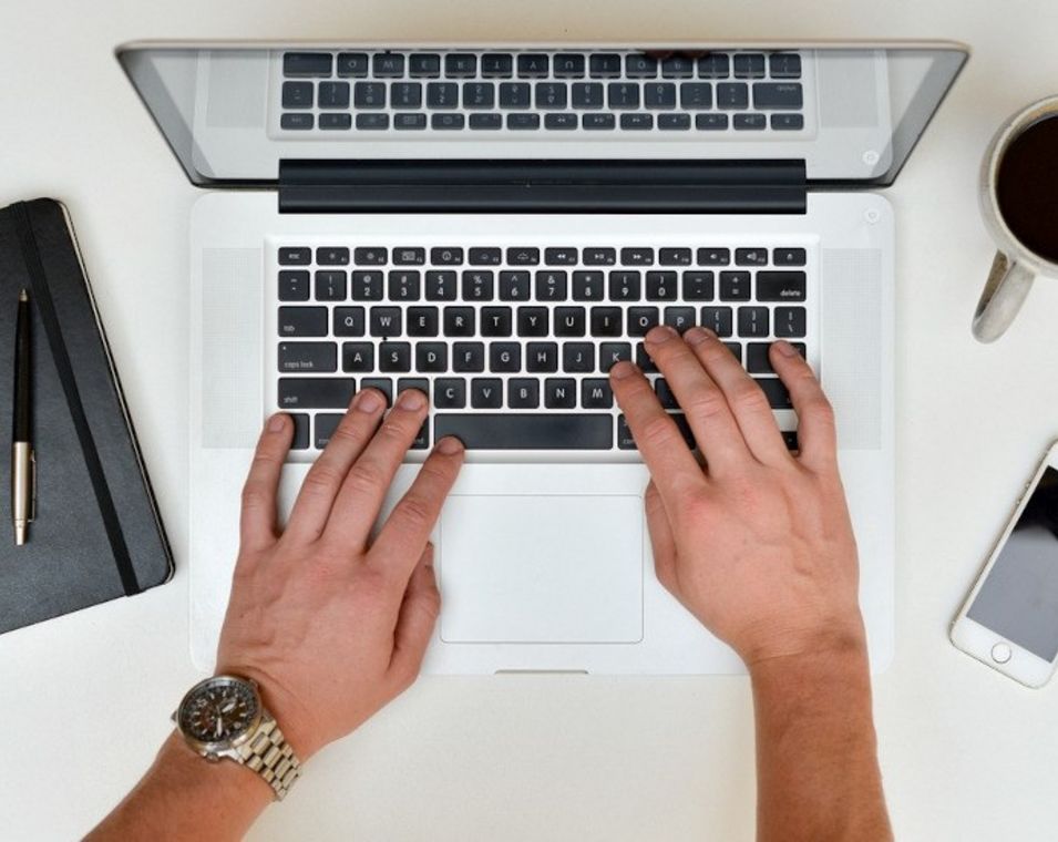Das Bild zeigt die Hände eines Mannes auf der Tastatur eines Laptops.