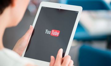 Frau hält ein Tablet mit dem Youtube-Logo auf dem Bildschirm