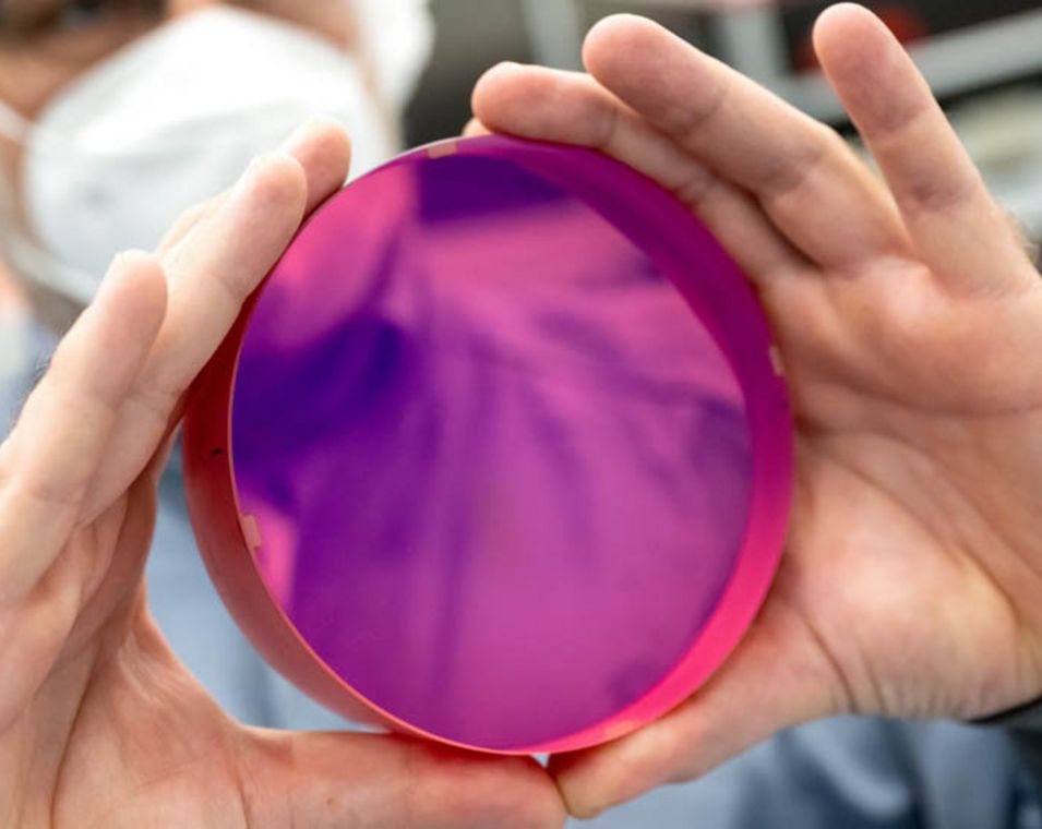 Wissenschaftler hält einen violetten Laserkristall in die Höhe