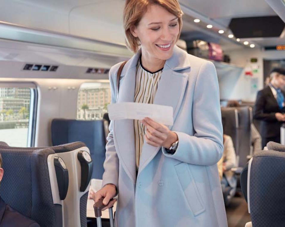 Frau im Zug mit Ticket und Koffer in der Hand